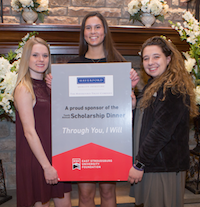 Students displaying Scholarship Dinner sign.